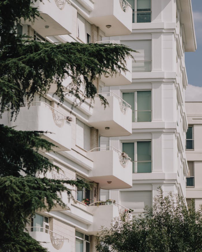 Stylish white apartment building with balconies nestled among greenery.